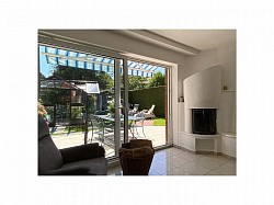 Helles Wohnzimmer mit gemauertem Kamin mit Wassertasche, Zugang zur Terrasse und Blick in den grünen Garten in Melle